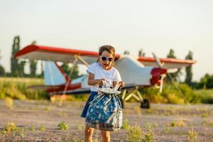 Child aviator with airplane dreams of traveling in summer in nature at sunset photo