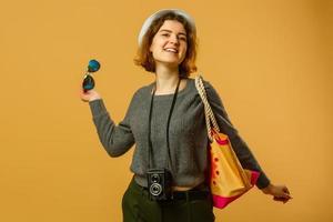 Traveler tourist woman in summer casual clothes, hat with suitcase isolated on yellow orange background. Female passenger traveling abroad to travel on weekends getaway. Air flight journey concept photo