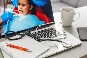 Workplace of doctor with laptop and stethoscope and notebook on white table top view shot photo