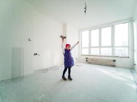 Excited cute child feel carefree having fun relocating into new home, funny little girl playing jumping enjoying move in big modern living room photo