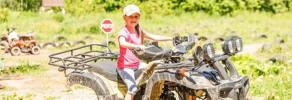 Little girl riding ATV quad bike in race track photo