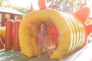 Happy little girl having lots of fun on a jumping castle during sliding photo