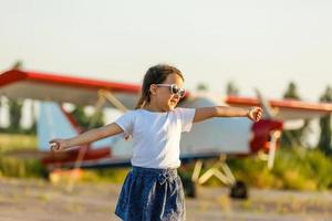 Child aviator with airplane dreams of traveling in summer in nature at sunset photo