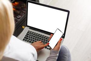 Mockup image of business woman using and typing on laptop with blank white screen and coffee cup on glass table in modern loft cafe photo