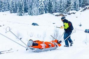 Ski rescue team with slide stretcher, brings help to ski during bad weather conditions. photo