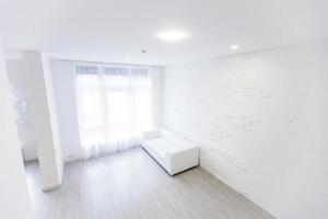 Empty waiting room with a modern gray sofa in front of the door and a clock on the wall photo