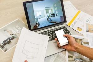 Construction engineer and architect's desk with house projects, laptop, tools and wood swatches top view, male hands drawing photo