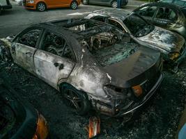 cars after the fire. Two burned out cars with an open hood. Arson, burnt car photo