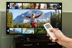 Smart tv and hand pressing remote control photo