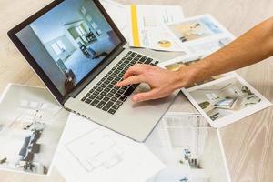 Decorator's hands with ruler on project drawings. Laptop, color swatches and tools on work table photo