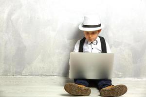 retrato del genio. niño trabajando en la computadora sentado en el suelo. estudiando. aprendizaje en línea de forma remota. escuela lejana. educación a distancia. cursos y conocimientos en línea. foto