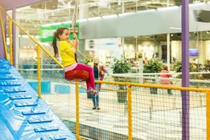 Child jumping on colorful playground trampoline. Kids jump in inflatable bounce castle on kindergarten birthday party Activity and play center for young child. Little girl playing outdoors in summer photo