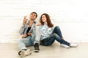 el hombre y la mujer felices se sientan en el fondo de la pared blanca foto