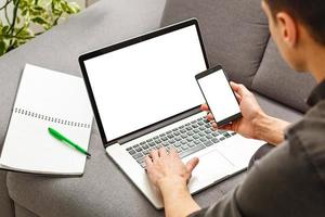 Silhouette of cropped shot of a young man working from home using smart phone and notebook computer, man's hands using smart phone in interior, man at his workplace using technology, flare light photo