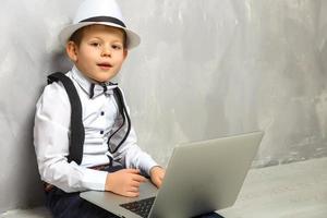 retrato del genio. niño trabajando en la computadora sentado en el suelo. estudiando. aprendizaje en línea de forma remota. escuela lejana. educación a distancia. cursos y conocimientos en línea. foto