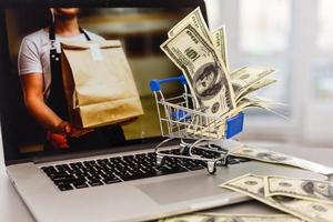 A small cart on a laptop background with money on a lighted table photo