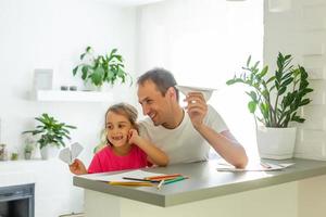 Handsome father and his cute little daughter are playing with paper planes and smiling while spending time together photo