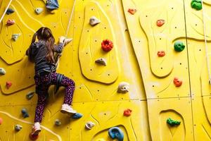 Little girl ascending in outdoor rock climbing gym photo