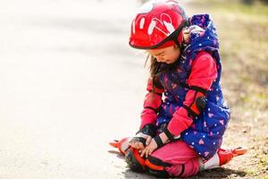 Girl with helmet on but without protective knee pads crying photo