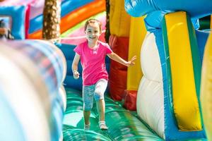 Happy little girl having lots of fun on a jumping castle during sliding. photo