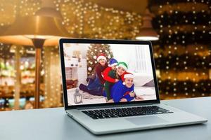 una familia feliz muestra un portátil junto a una chimenea en la mesa. computadoras portátiles foto