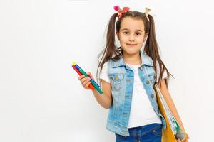 feliz y dulce colegiala que lleva mochila escolar y libros sonriendo en educación y concepto de regreso a la escuela aislado en fondo blanco foto