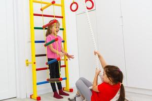 Active friends climbing up the wall bars in gym photo