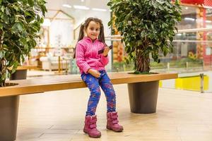 niña pequeña jugando con un smartphone en un moderno centro comercial de supermercados. foto