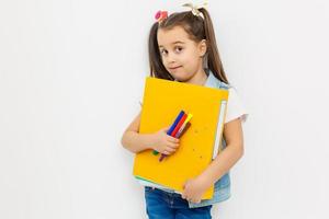 happy sweet little school girl carrying schoolbag backpack and books smiling in education and back to school concept isolated on white background photo