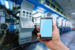 Hand holding smartphone against shelves with boxes in warehouse photo