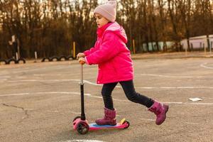 little beautiful girl riding scooter at stadium photo