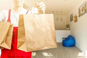 Diverse of paper containers for takeaway food. Delivery man is carrying photo