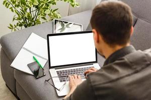 imagen recortada de un joven que trabaja en su computadora portátil en una cafetería, vista trasera de un hombre de negocios ocupado usando una computadora portátil en el escritorio de la oficina, escribiendo en una computadora sentada en una mesa de madera foto