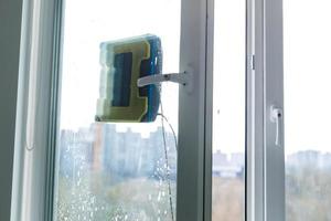 Robot window cleaner work on dirty window. Cleaning the house with smart devices. Automatic vacuum robots for cleaning windows, an assistant for the home. photo