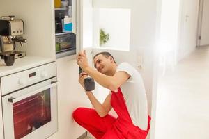 Repairman makes refrigerator appliance troubleshooting and maintenance works photo