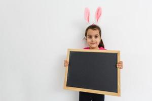 Little girl playing Baby on Easter egg hunt Kids play . Heart form blank chalk board for your text photo