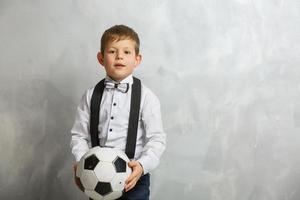 niño pequeño con una pelota de fútbol en un fondo gris foto