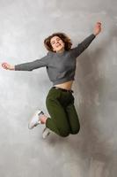 Full length portrait of a cheerful casual asian woman jumping isolated over gray background photo