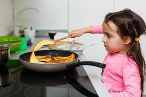 una niña hermosa con un vestido polvoriento se sienta detrás de la paja en la cocina y mira hacia otro lado, en primer plano, en el interior foto