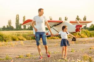 Father and daughter are happy with the plane on the meadow. photo