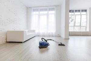 Vacuum cleaner on white concrete background in the house. photo