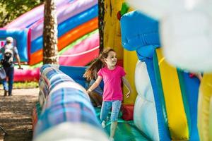 niña feliz divirtiéndose mucho en un castillo de salto durante el deslizamiento. foto