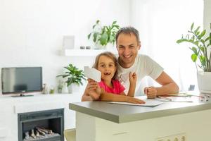 Handsome father and his cute little daughter are playing with paper planes and smiling while spending time together photo