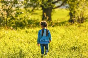 little girl alone on the meadow in summer day photo