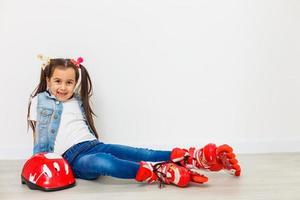 Happy little girl with roller skates and protective gear resting - isolated photo