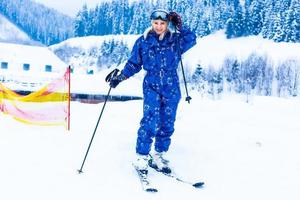 retrato de un bonito esquiador con overoles azules en una estación de esquí foto