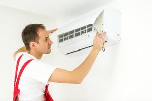Young worker installs air conditioner in the room with blue walls photo