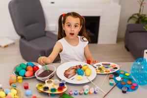 little girl having fun to paint easter eggs photo