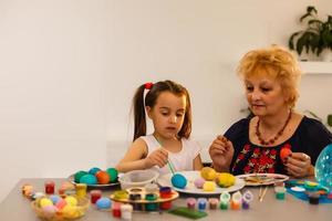 Grandmother with granddaughter are coloring eggs for Easter. photo