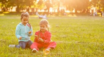 Two little girls sitting on grass photo